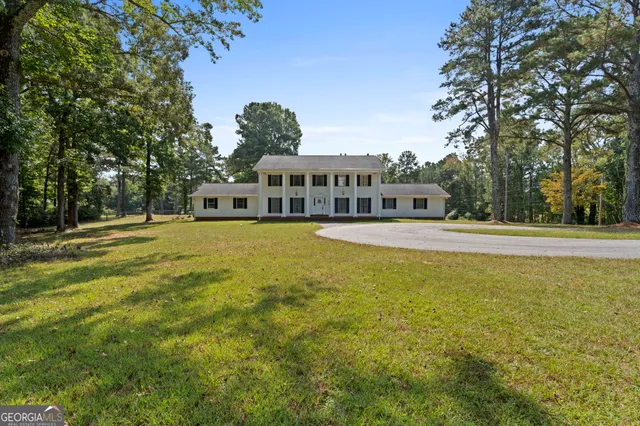 a view of a house with a big yard and large trees