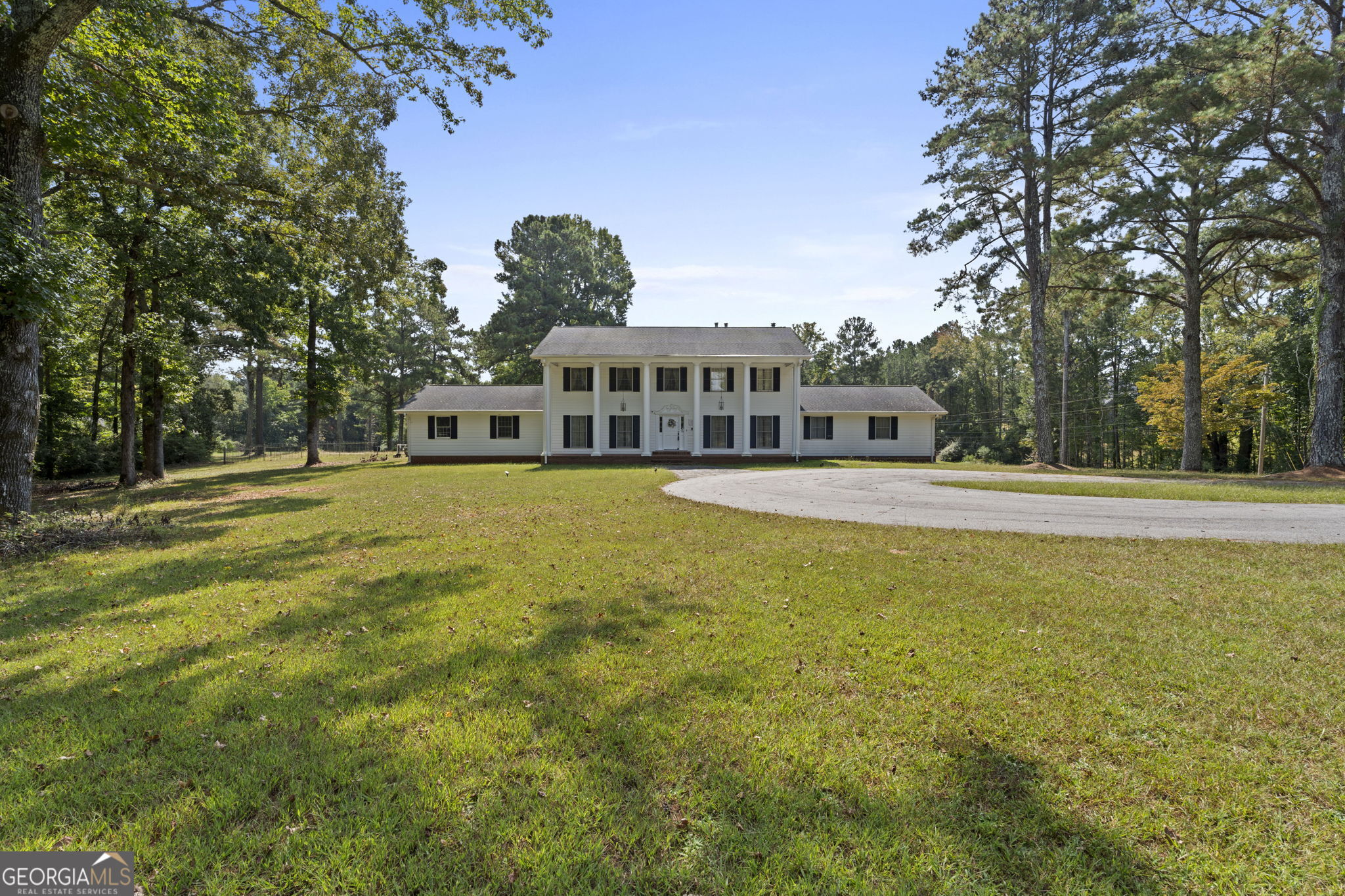 a view of a house with a big yard and large trees