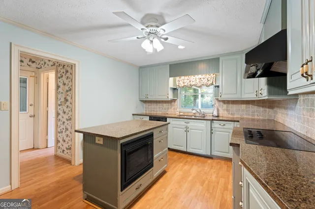 a kitchen with kitchen island granite countertop a sink cabinets and stainless steel appliances