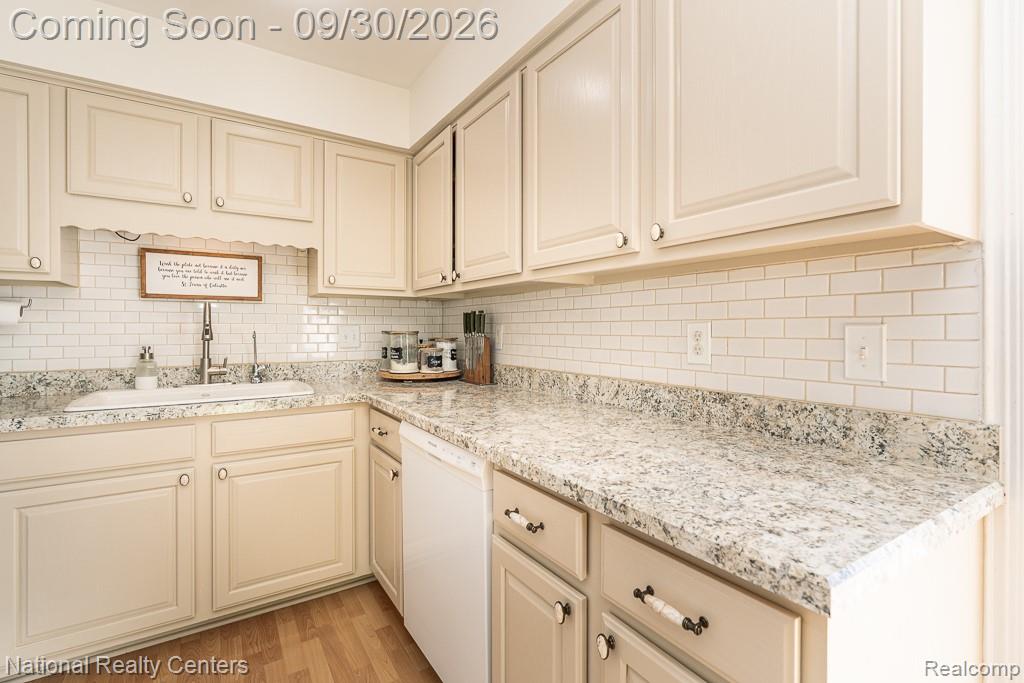 67976 Van Dyke Road, Unit 15 Washington, MI 48095 - Photo 11 of 35 Wood-finish flooring, light-toned cabinetry, subway tile backsplash, light-toned countertop, and an integrated kitchen sink
