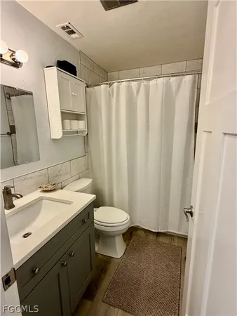 a bathroom with a sink a toilet a mirror and shower curtain
