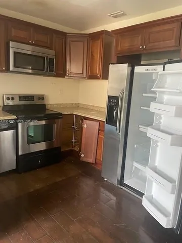 a utility room with stainless steel appliances wooden cabinets and a stove top oven