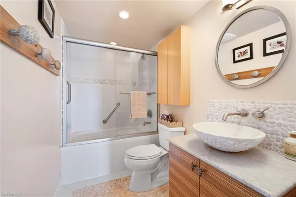 a bathroom with a granite countertop sink mirror vanity and toilet