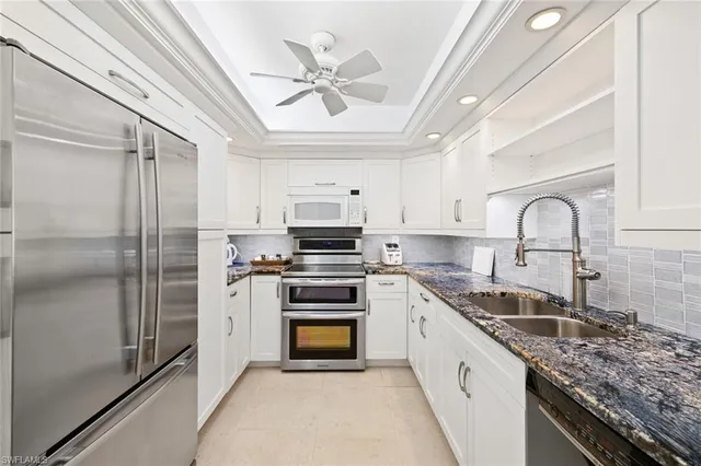 a kitchen with stainless steel appliances granite countertop a sink a stove a refrigerator cabinets and a window