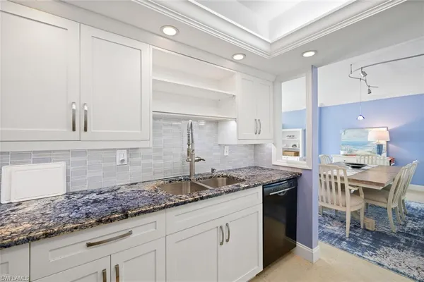 a kitchen with granite countertop a sink a stove and cabinets