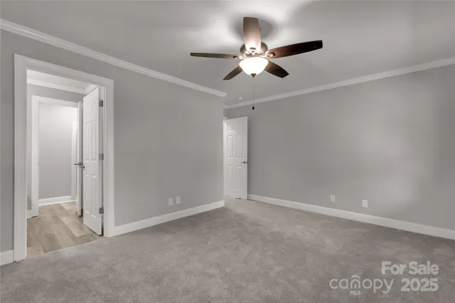 a view of an empty room with a chandelier fan