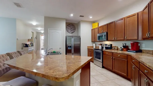 a kitchen with kitchen island granite countertop a sink a counter top space and stainless steel appliances