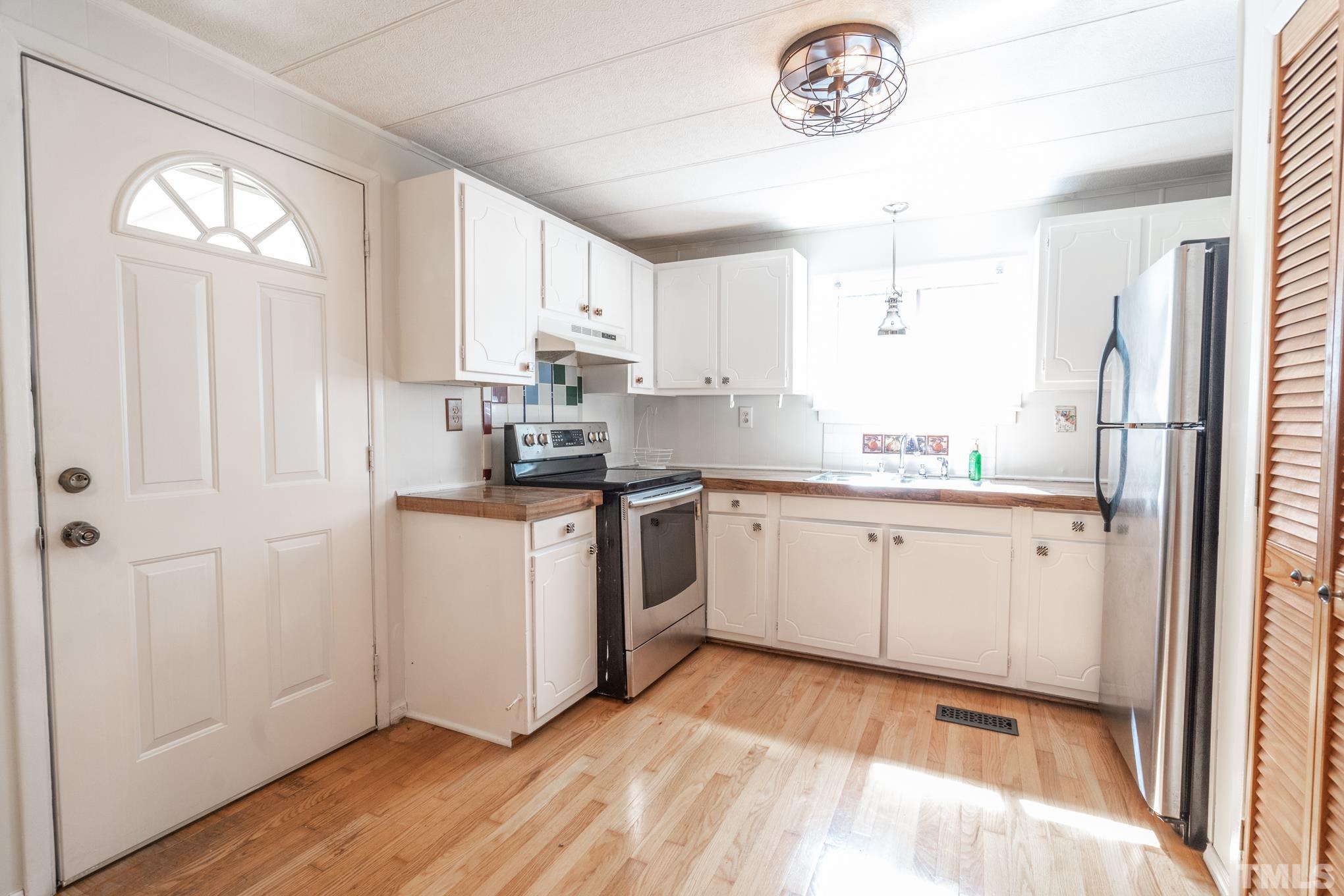 109 Old Watkins Road Henderson, NC 27537 - Photo 11 of 12 a kitchen with a refrigerator a stove a microwave and cabinets