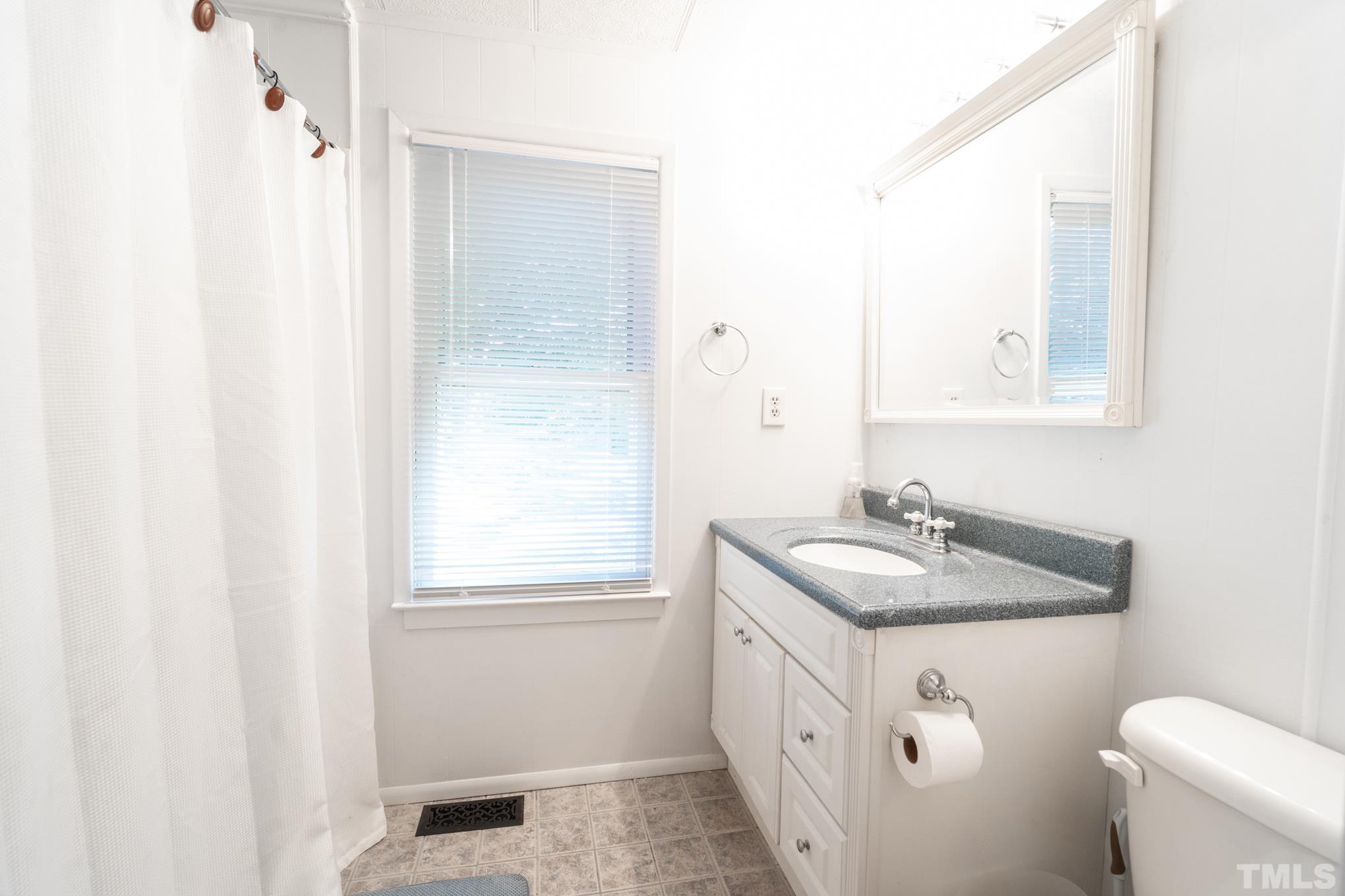 109 Old Watkins Road Henderson, NC 27537 - Photo 8 of 12 a bathroom with a sink and mirror with toilet