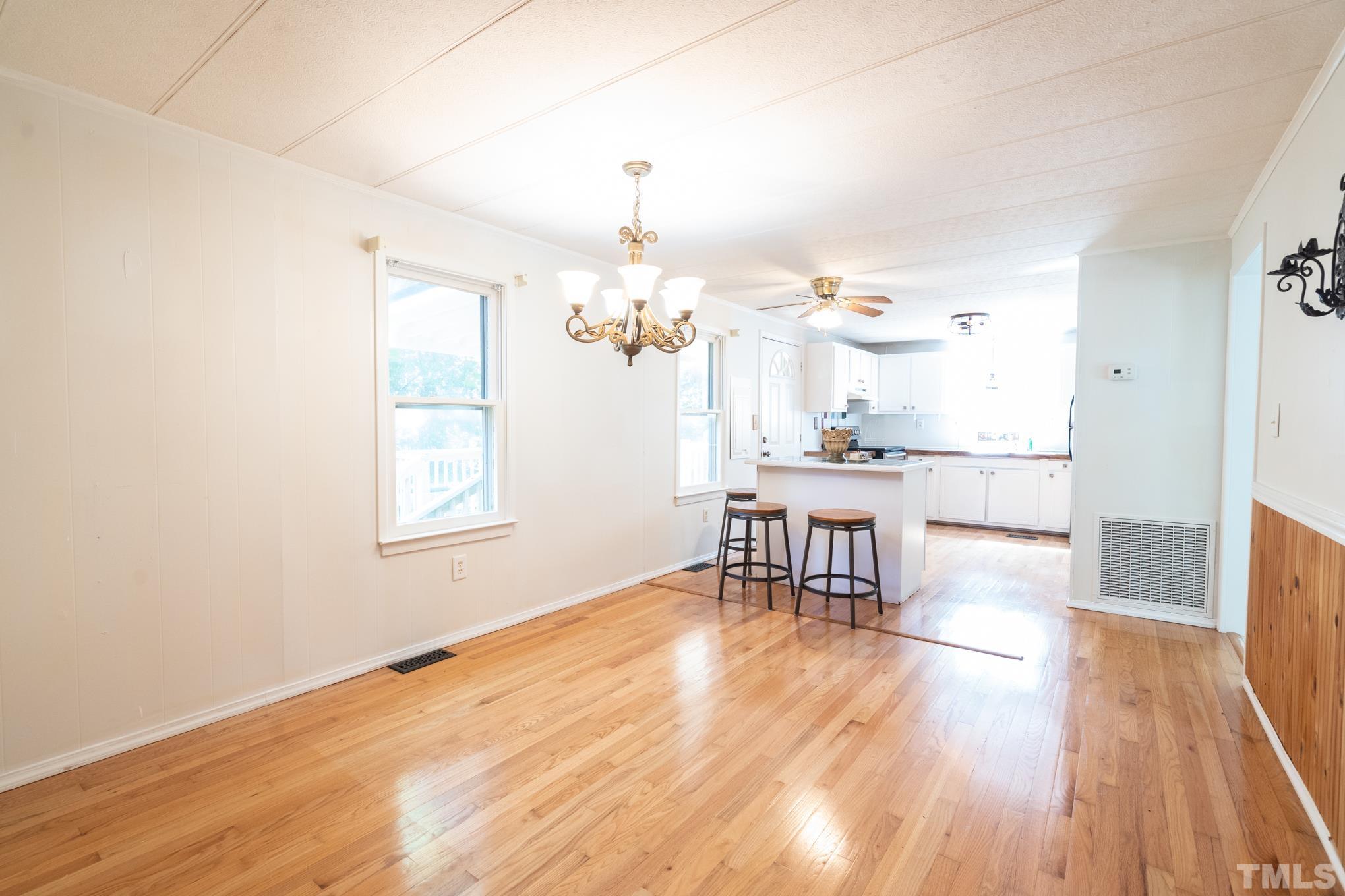 109 Old Watkins Road Henderson, NC 27537 - Photo 9 of 12 a dining room with wooden floor a chandelier a glass table and chairs