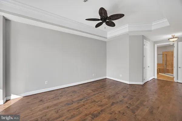 an empty room with wooden floor chandelier fan and windows