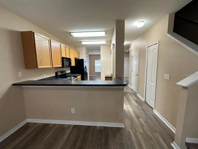 a living room with stainless steel appliances wooden floors wooden cabinets and a fireplace