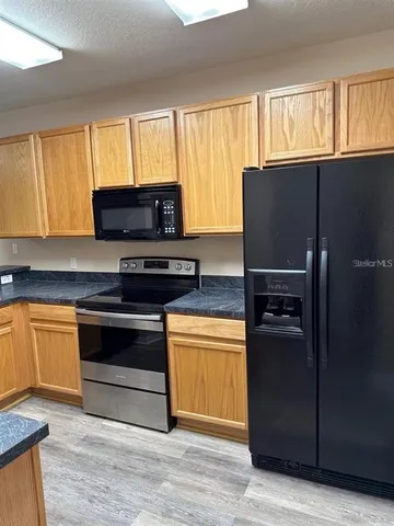 a kitchen with granite countertop a refrigerator stove and microwave