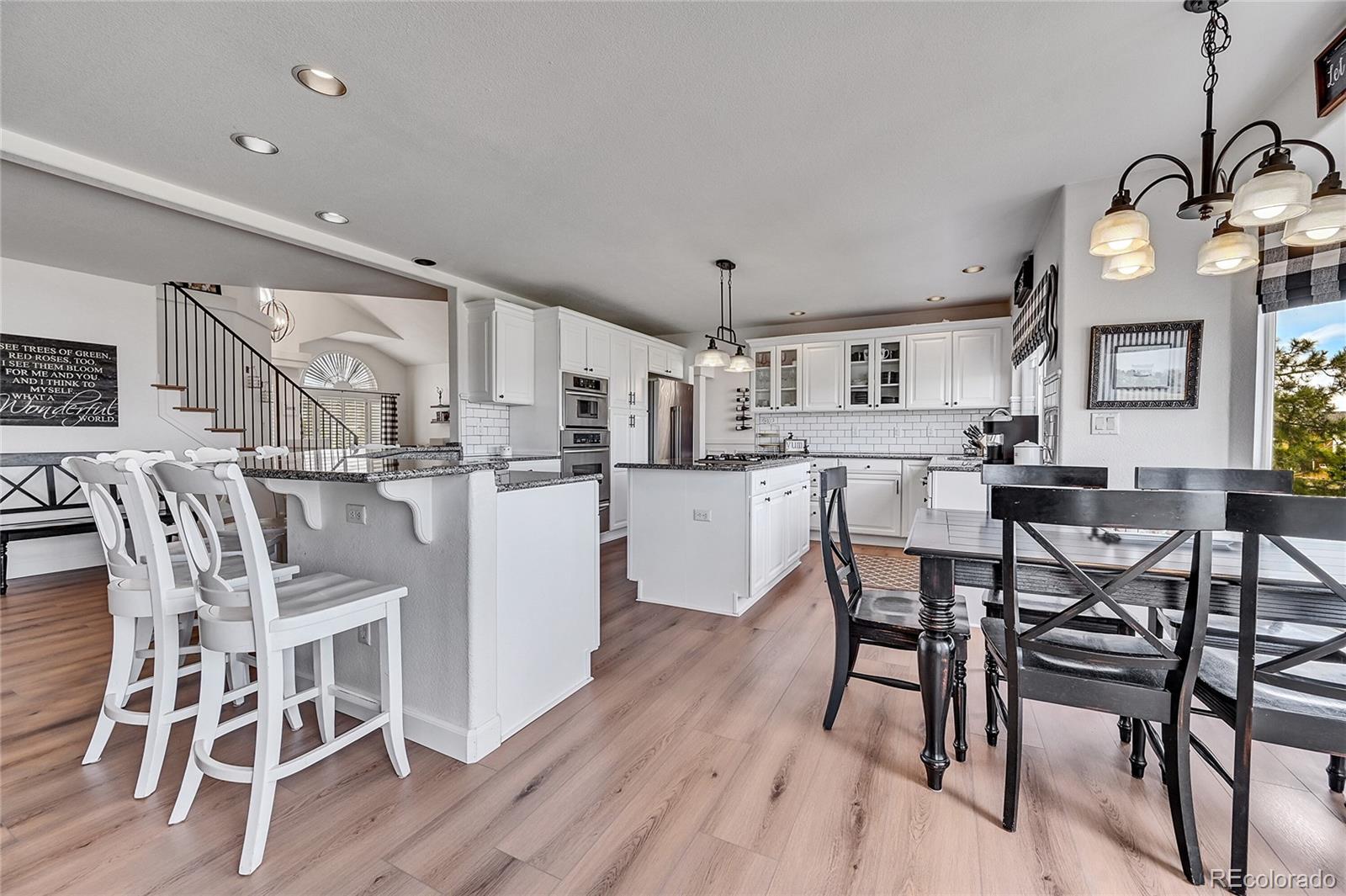 a kitchen with stainless steel appliances a dining table chairs stove and white cabinets