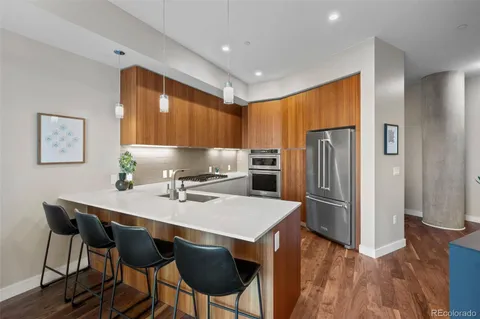 a kitchen with stainless steel appliances a dining table chairs refrigerator and sink