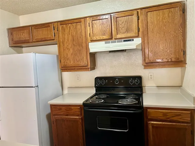 a kitchen with granite countertop a refrigerator stove and cabinets