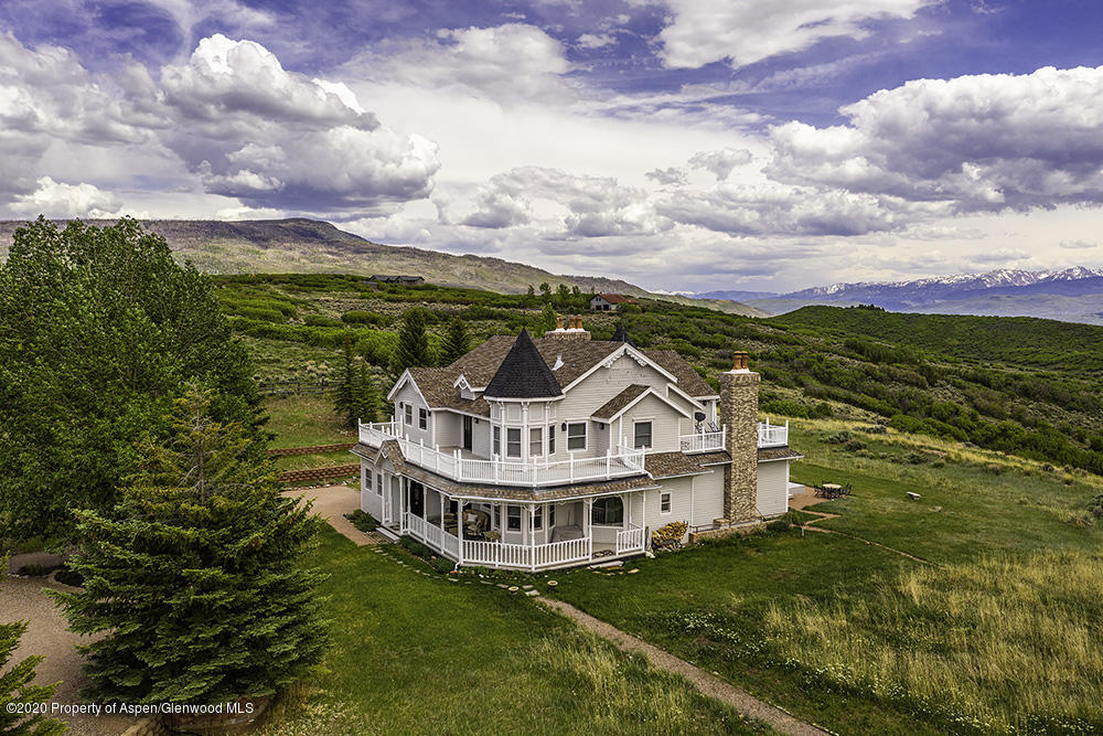 a view of a big house with a big yard and large trees
