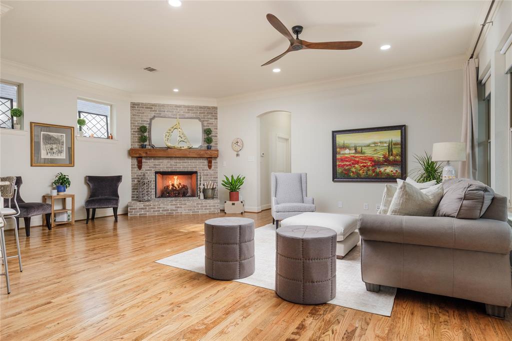 2205 State Boulevard McKinney, TX 75071 - Photo 11 of 40 Living room featuring ornamental molding, arched walkways, a brick fireplace, light wood-style flooring, and a ceiling fan