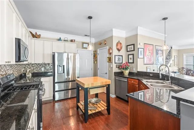 a kitchen with stainless steel appliances granite countertop a refrigerator a sink and a stove