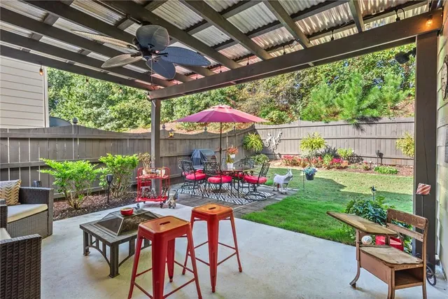 a patio with a patio table and chairs with a small yard