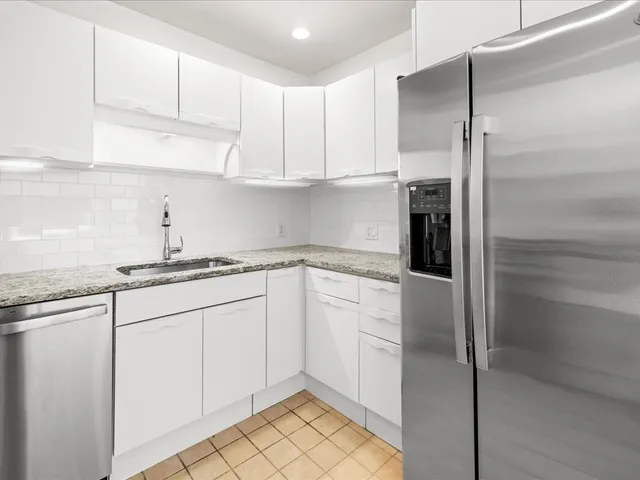 a kitchen with granite countertop white cabinets and white appliances