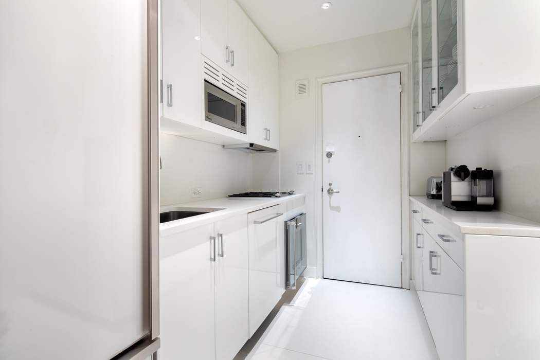 781 5th Avenue, Unit 505 Manhattan, NY 10022 - Photo 3 of 14 a kitchen with white cabinets and white appliances