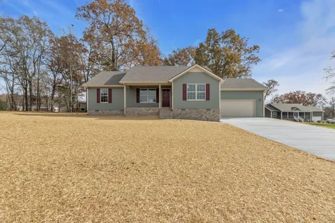 a front view of a house with a yard covered with snow and trees