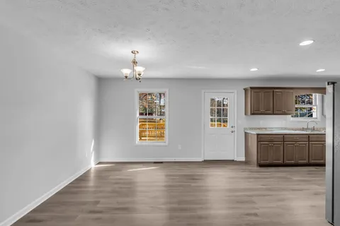 a view of an empty room with a kitchen and a window