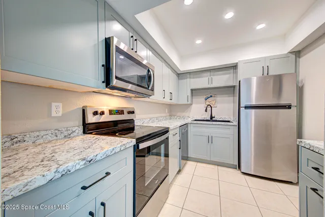 a kitchen with stainless steel appliances granite countertop a refrigerator a stove and a sink