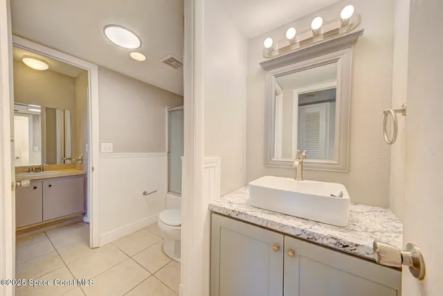 a spacious bathroom with a granite countertop sink a toilet and a mirror