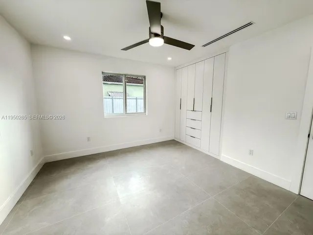 an empty room with a window and a ceiling fan