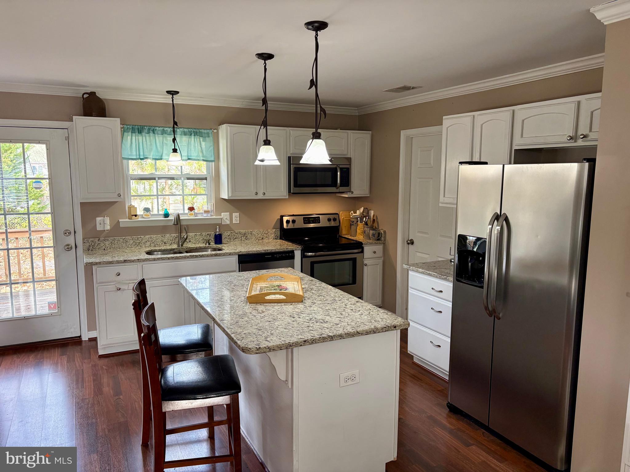 45394 Walnut Street Piney Point, MD 20674 - Photo 4 of 23 a kitchen with stainless steel appliances granite countertop a refrigerator a sink dishwasher a stove a dining table and chairs with wooden floor