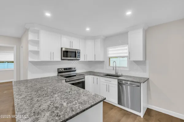 a kitchen with granite countertop stainless steel appliances and white cabinets