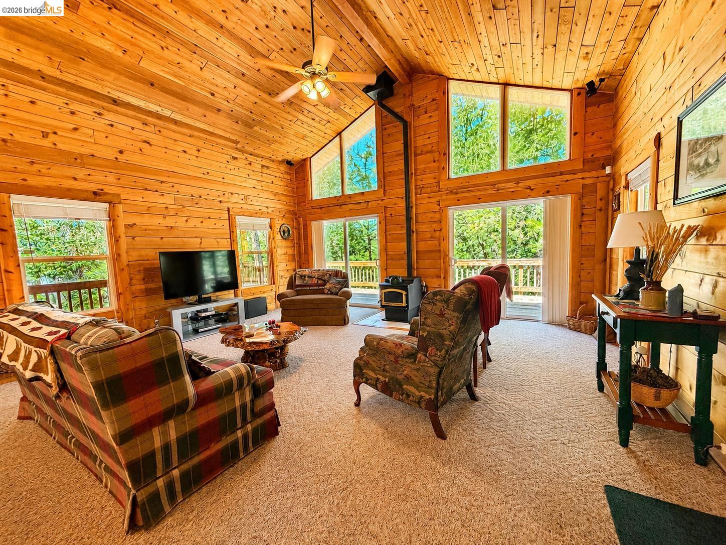 21181 Phoenix Lake Road Sonora, CA 95370 - Photo 9 of 34 Spacious living area featuring expansive wood paneling, a vaulted wood-plank ceiling, and a ceiling fan