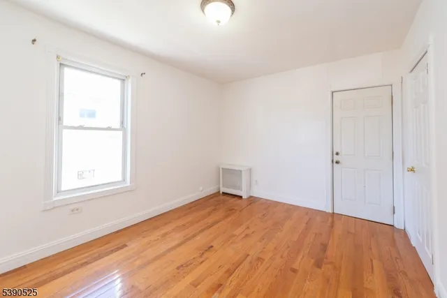 an empty room with wooden floor closet and windows