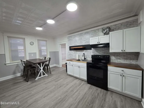a kitchen with granite countertop a sink cabinets and wooden floor