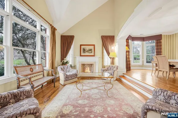a living room with furniture large wooden floor and floor to ceiling windows