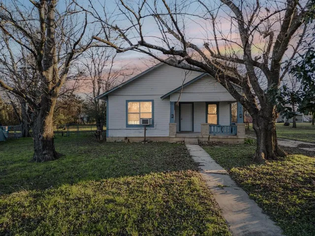 a front view of a house with a garden and trees