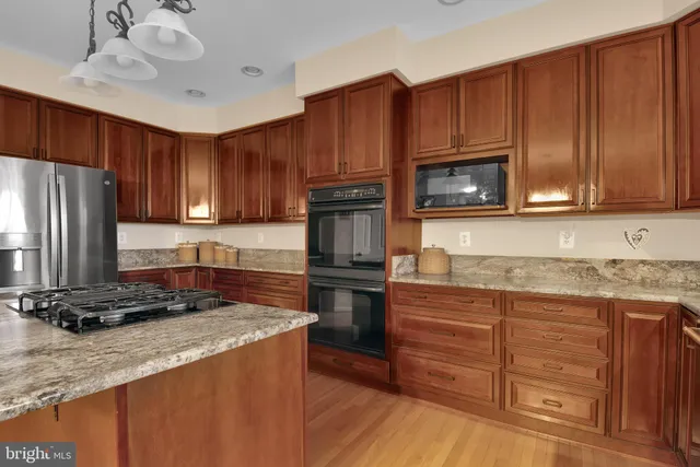 a kitchen with granite countertop wooden cabinets a stove a oven and a refrigerator with wooden floor