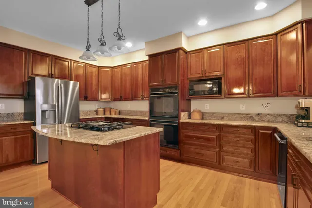 a kitchen with wooden cabinets stainless steel appliances a sink and a center island