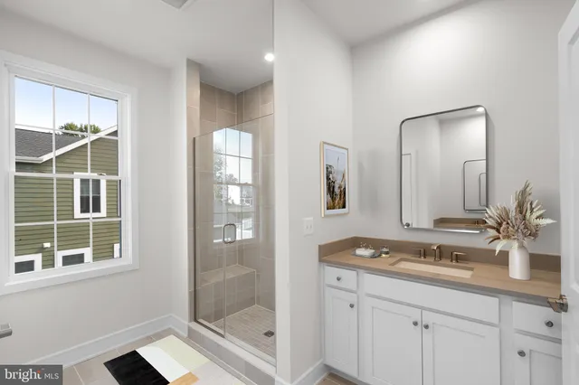 a bathroom with a granite countertop sink a mirror and a glass door shower