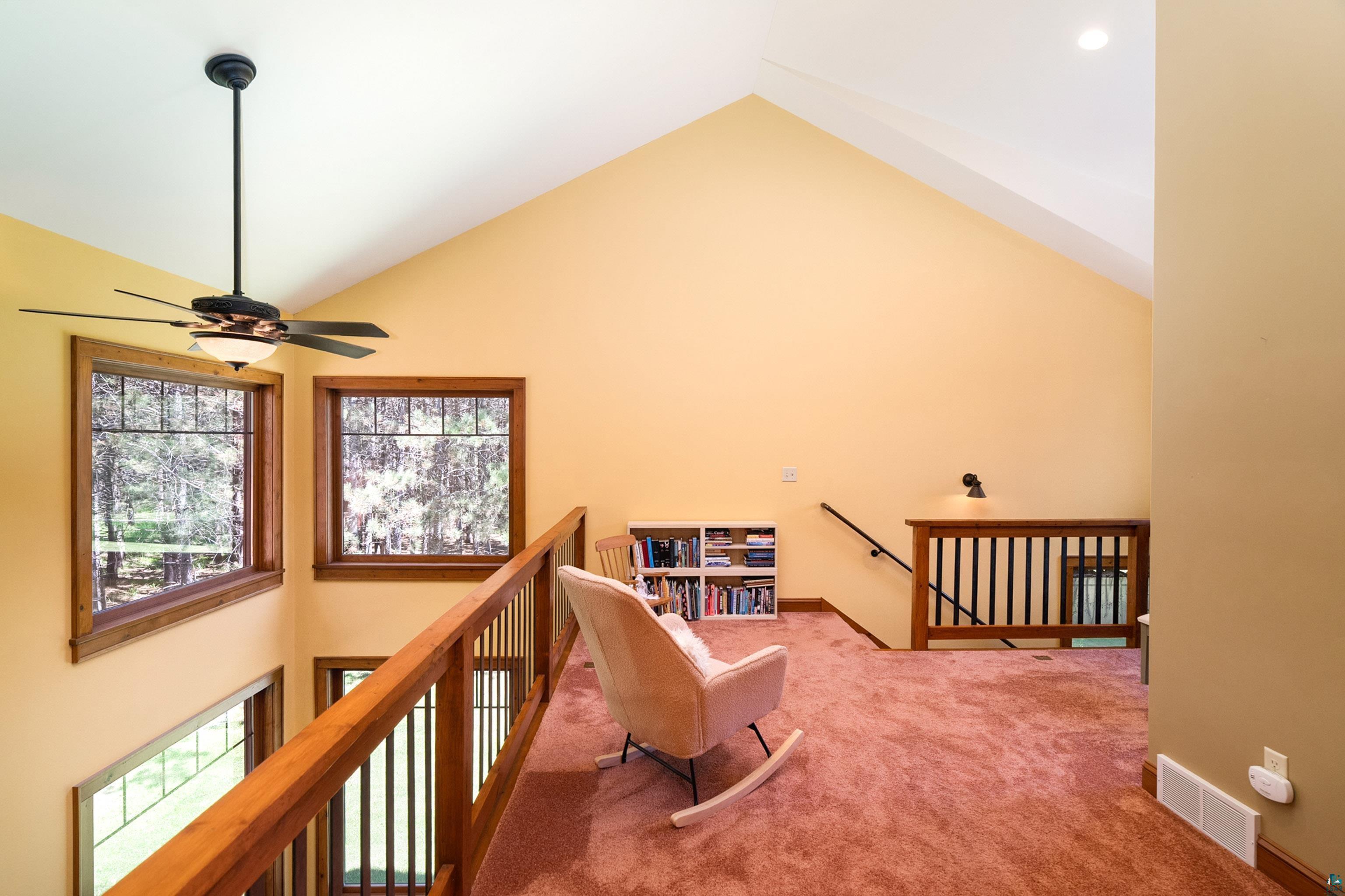 75 East Stark Road Esko, MN 55733 - Photo 28 of 87 Vaulted ceiling loft area featuring wood-framed windows, a ceiling fan with integrated lighting, and carpeted flooring