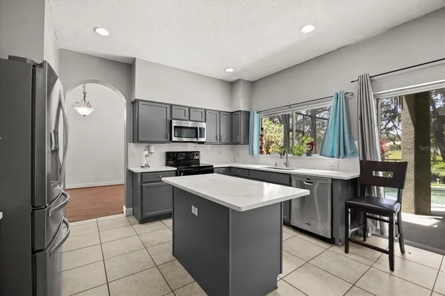 a kitchen with stainless steel appliances a sink a stove a refrigerator cabinets and a dining table