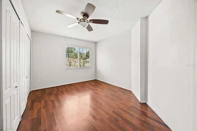 a view of room with hardwood floor and a ceiling fan