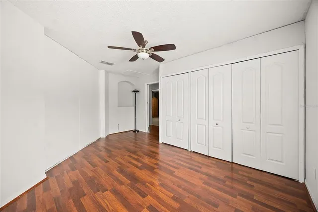 a view of empty room with wooden floor and fan