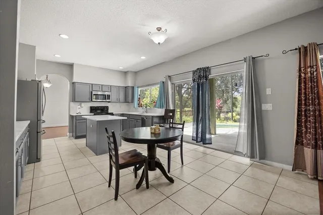 a kitchen with stainless steel appliances kitchen island granite countertop a refrigerator a stove a sink dishwasher and white cabinets with wooden floor