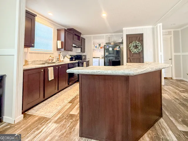 a large kitchen with kitchen island granite countertop a sink and cabinets