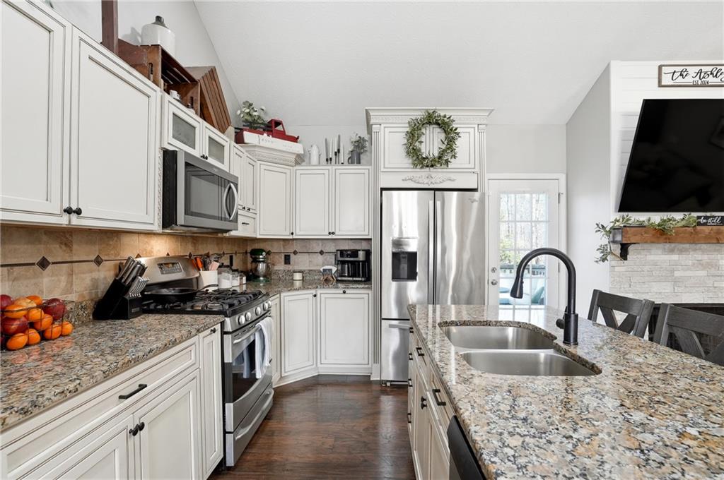 378 Baugh Street Commerce, GA 30529 - Photo 11 of 35 a kitchen with granite countertop a sink and a stove top oven with wooden floor