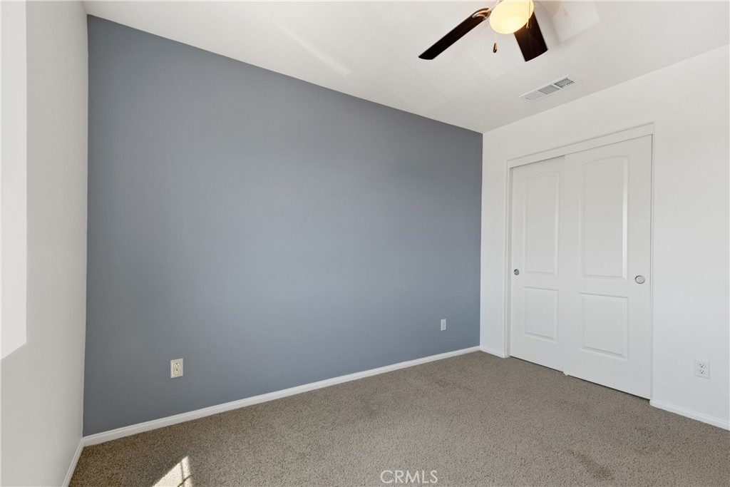11738 Murray Way Beaumont, CA 92223 - Photo 27 of 45 an empty room with a ceiling fan and carpet