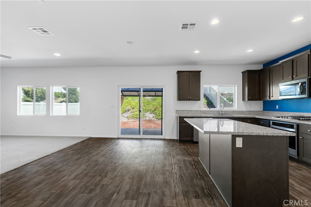 11738 Murray Way Beaumont, CA 92223 - Photo 5 of 45 a kitchen with kitchen island a stove a sink and a microwave